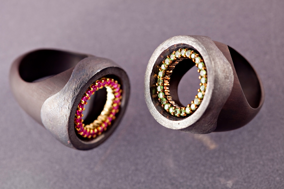 black hole rings in rubies and green sapphire set in yellow gold oxidized silver and ebony base